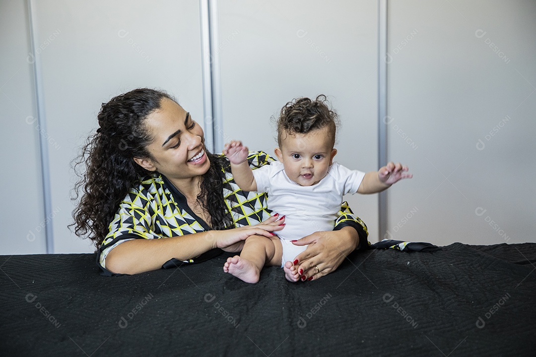 Uma mãe com seu bebê na cama brincando