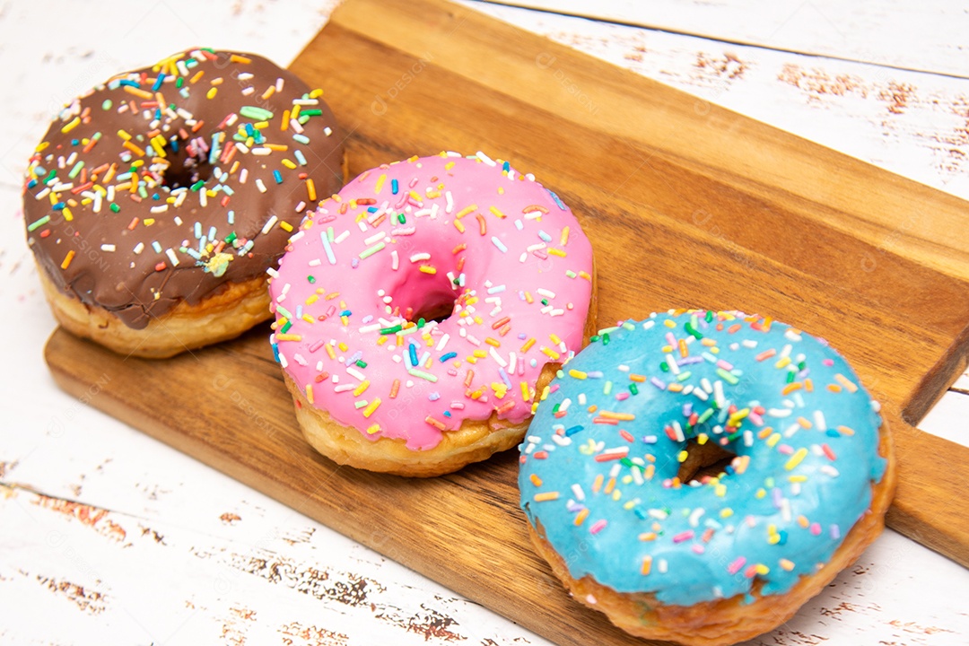 Rosquinhas com cobertura azul rosa e chocolate sobre uma tábua