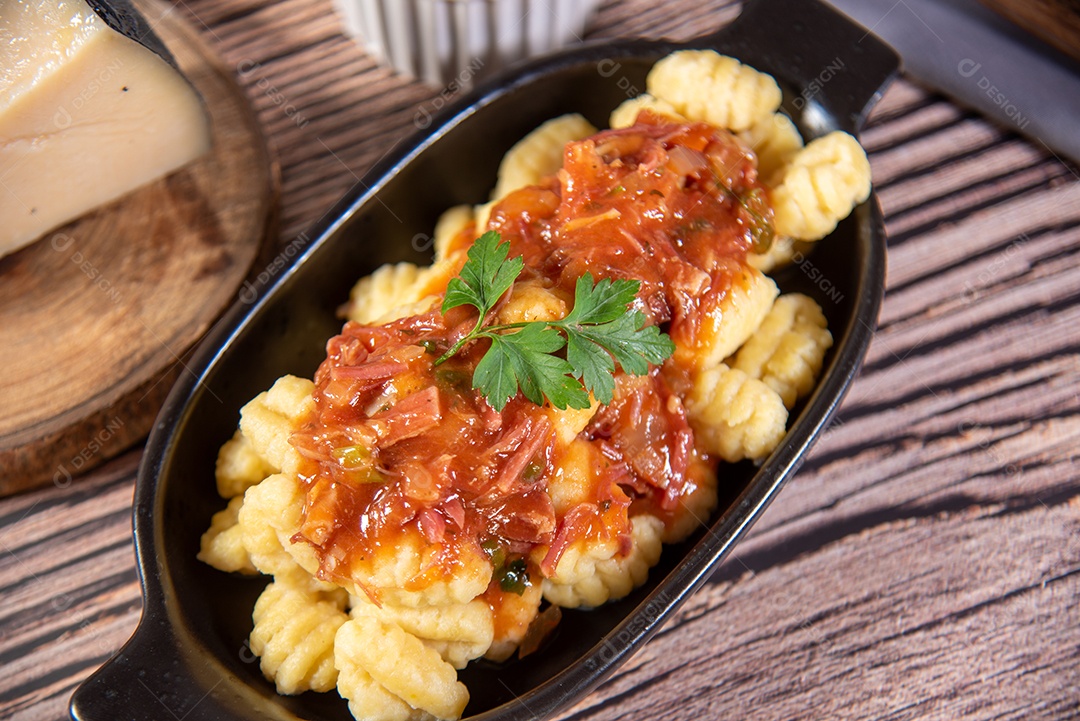 Nhoque com queijo parmesão molho de tomate sobre uma mesa de madeira