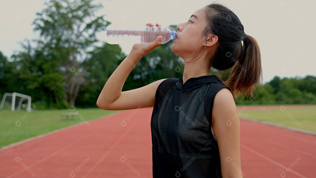 Uma mulher está bebendo água enquanto está em uma pista
