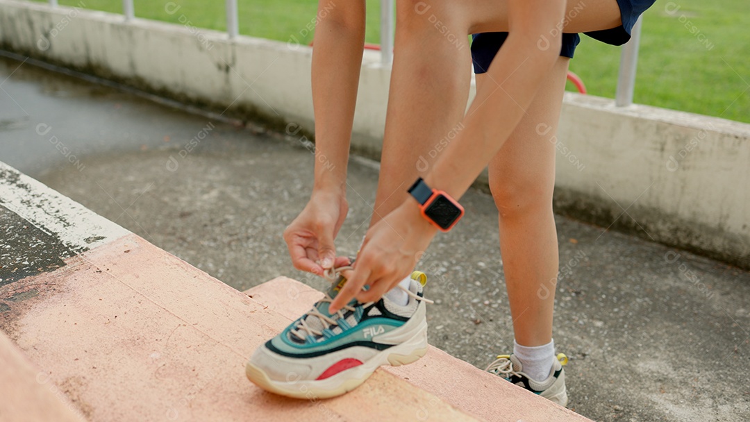 Uma mulher está calçando os sapatos em um degrau de concreto