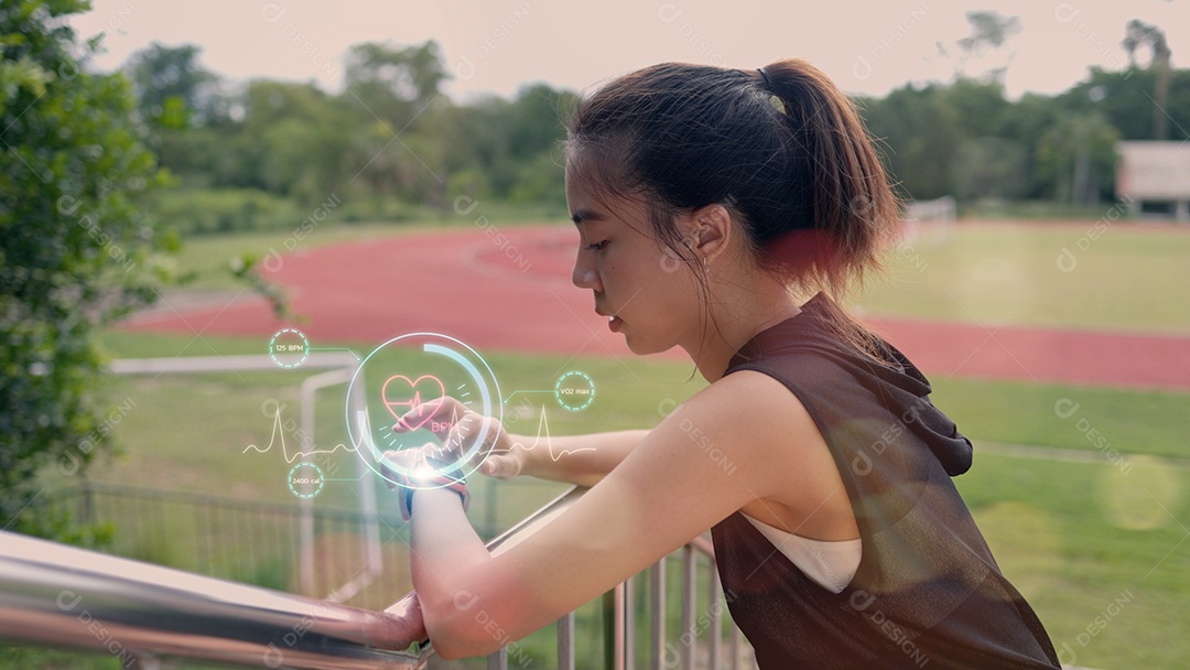 Uma mulher usando um relógio inteligente está em um campo gramado