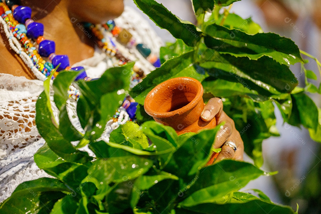 Vaso de barro na mão de uma mulher durante festa de Iemanjá