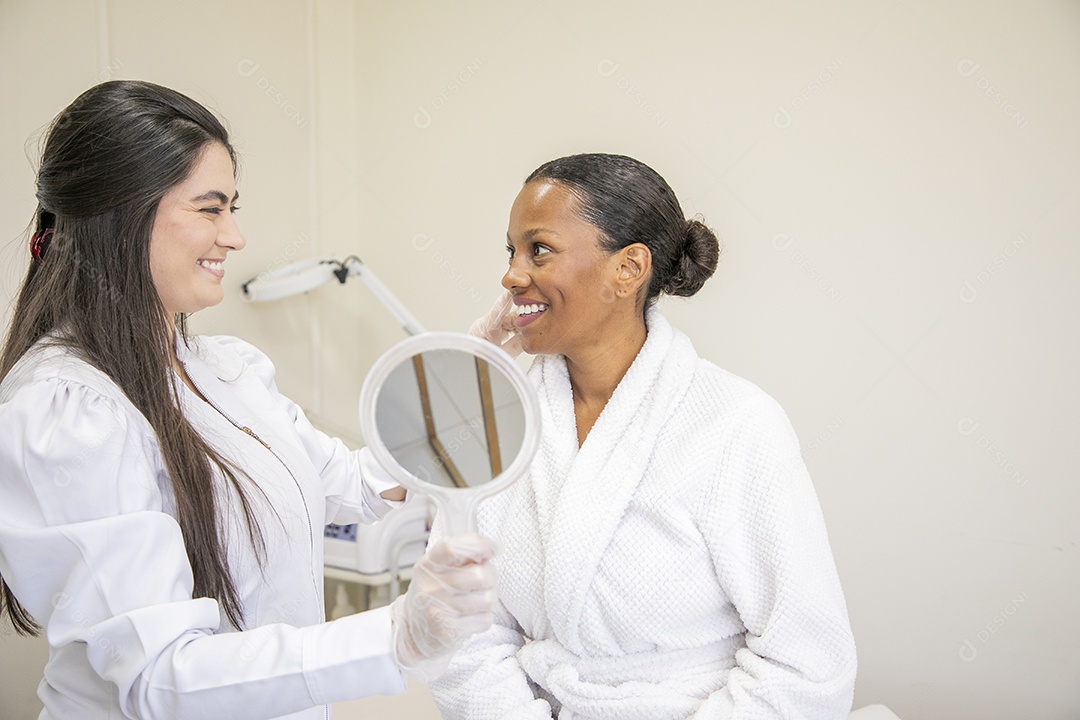 Esteticista fazendo protocolo em cliente que esta feliz