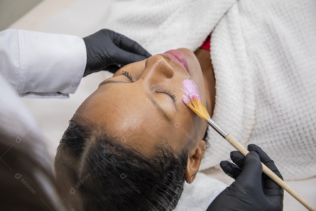 Esteticista passando mascara facial em cliente