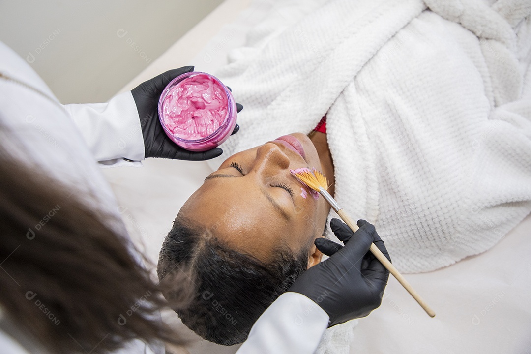 Esteticista passando máscara facial em cliente
