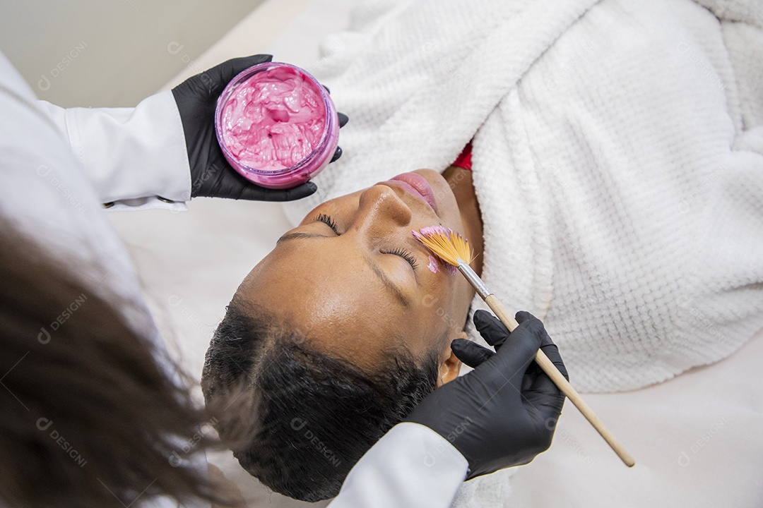 Esteticista usando mascara facial em cliente