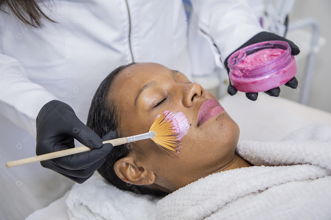 Esteticista aplicando procedimento na cliente com máscara