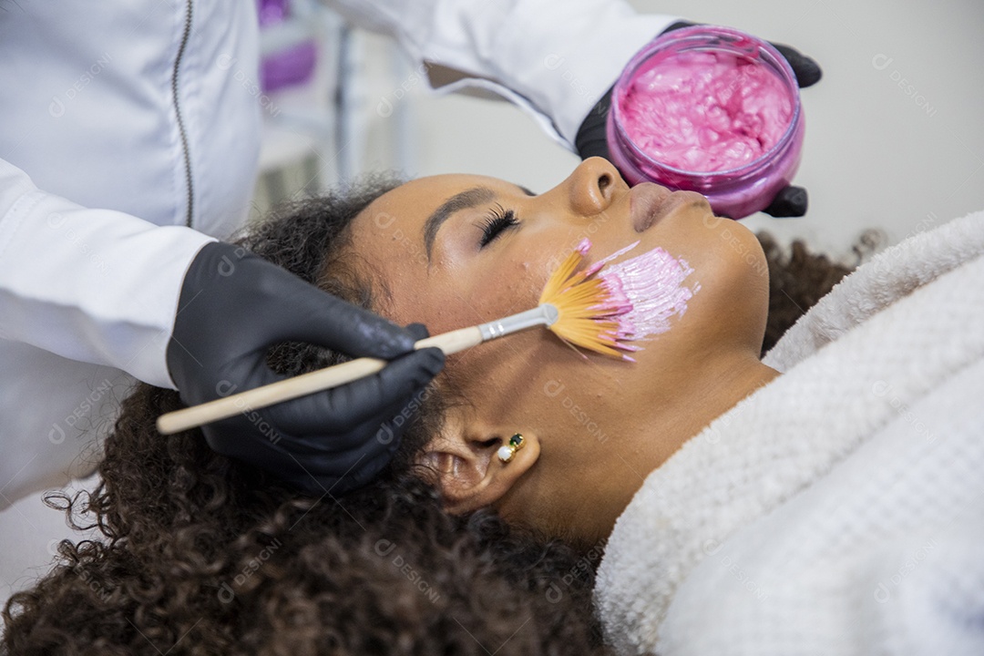 Esteticista passando máscara facial em uma jovem