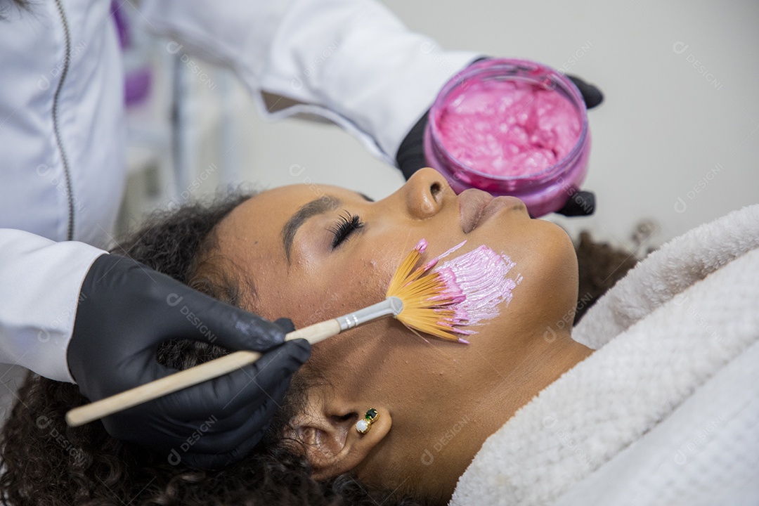 Esteticista passando máscara facial em uma jovem