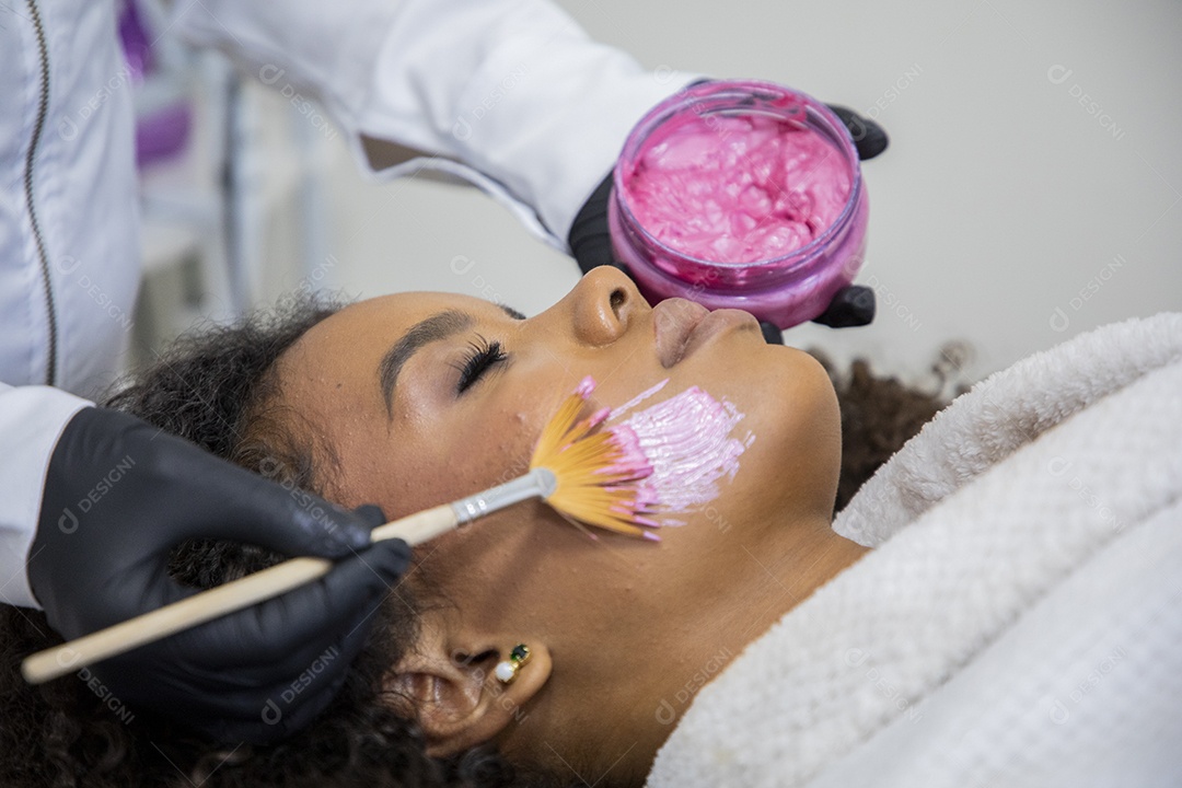 Esteticista passando máscara facial em uma jovem