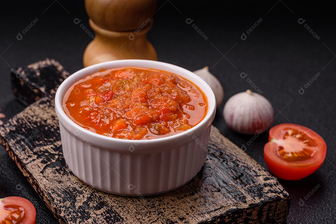 Molho encarnado ou picante com pimenta, tomate, alho, especiarias e ervas em um fundo escuro de concreto