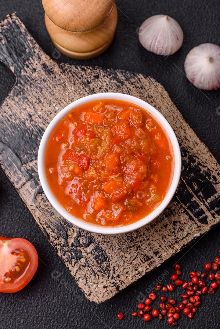 Molho encarnado ou picante com pimenta, tomate, alho, especiarias e ervas em um fundo escuro de concreto