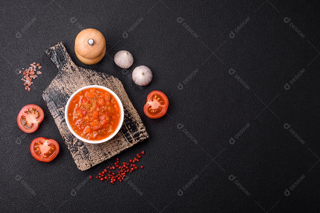 Molho encarnado ou picante com pimenta, tomate, alho, especiarias e ervas em um fundo escuro de concreto