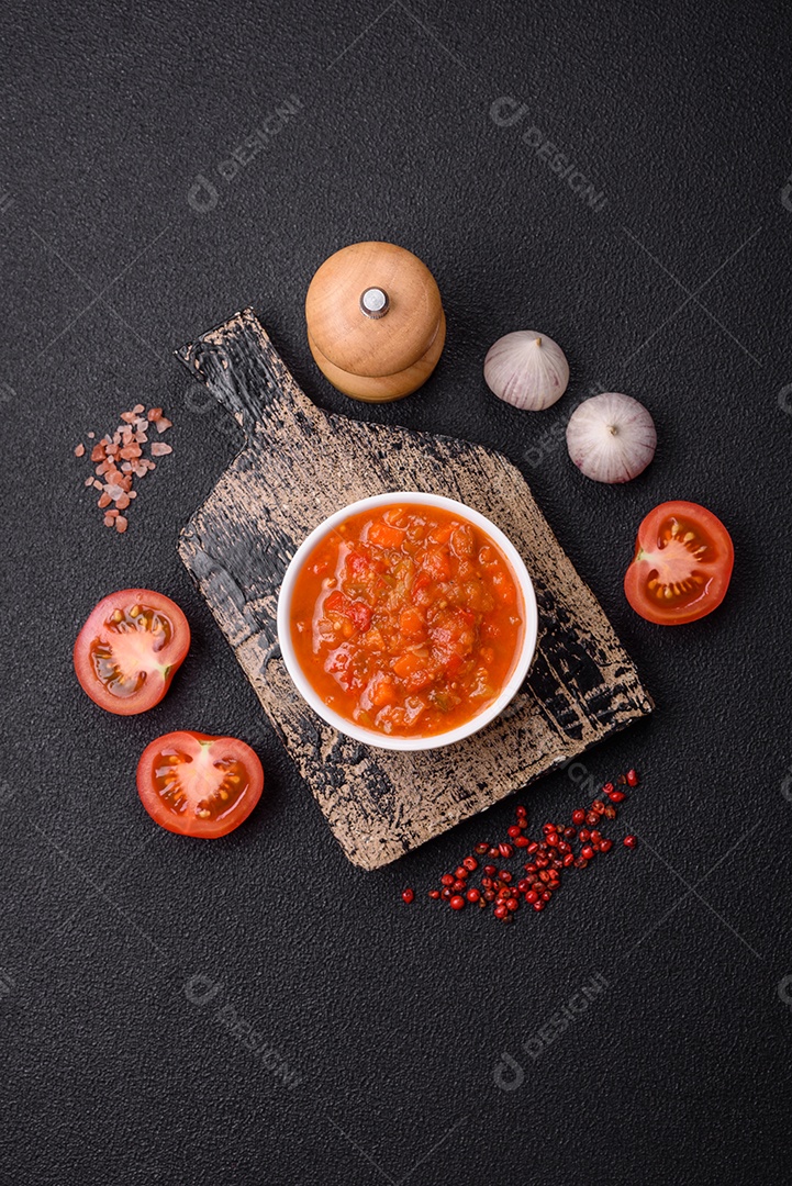 Molho encarnado ou picante com pimenta, tomate, alho, especiarias e ervas em um fundo escuro de concreto