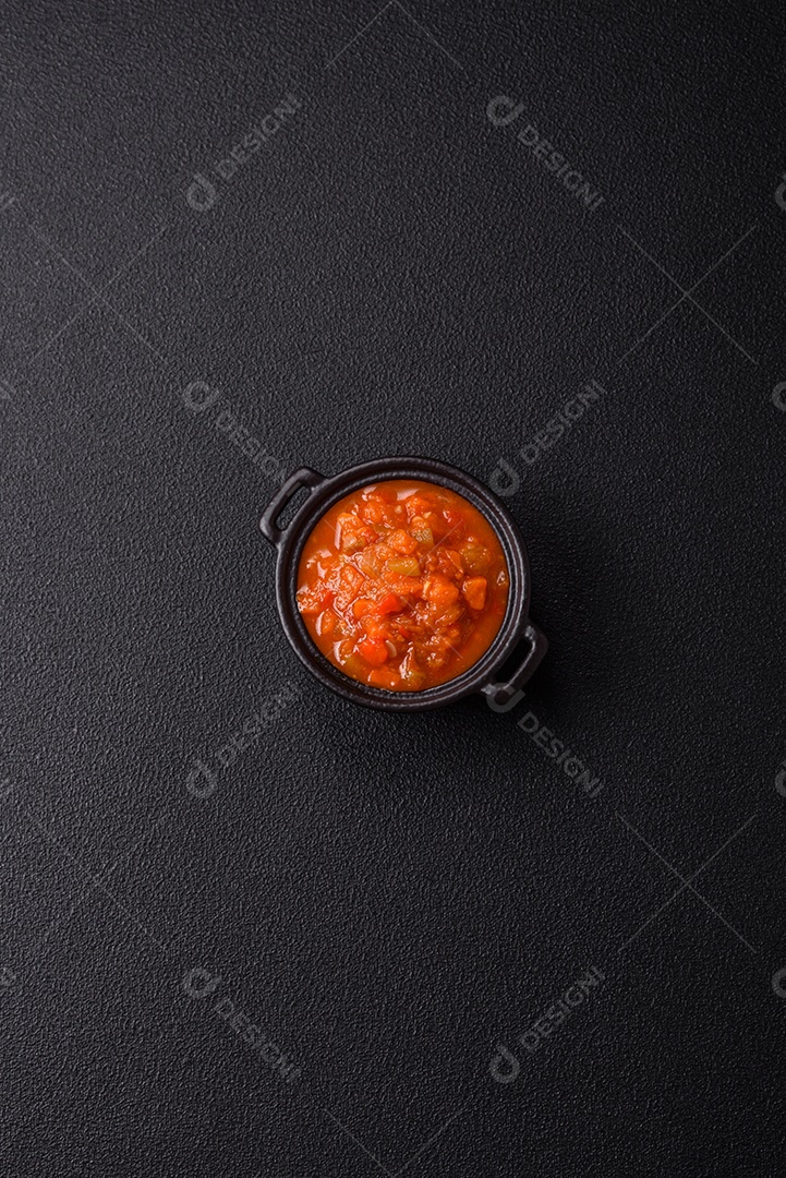 Molho encarnado ou picante com pimenta, tomate, alho, especiarias e ervas em um fundo escuro de concreto