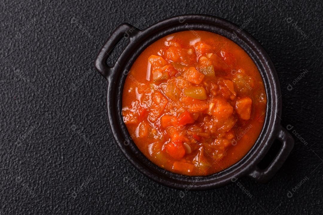 Molho encarnado ou picante com pimenta, tomate, alho, especiarias e ervas em um fundo escuro de concret