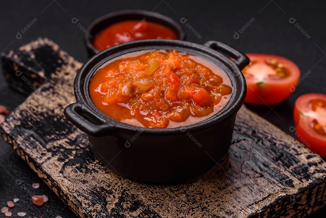 Molho encarnado ou picante com pimenta, tomate, alho, especiarias e ervas em um fundo escuro de concreto
