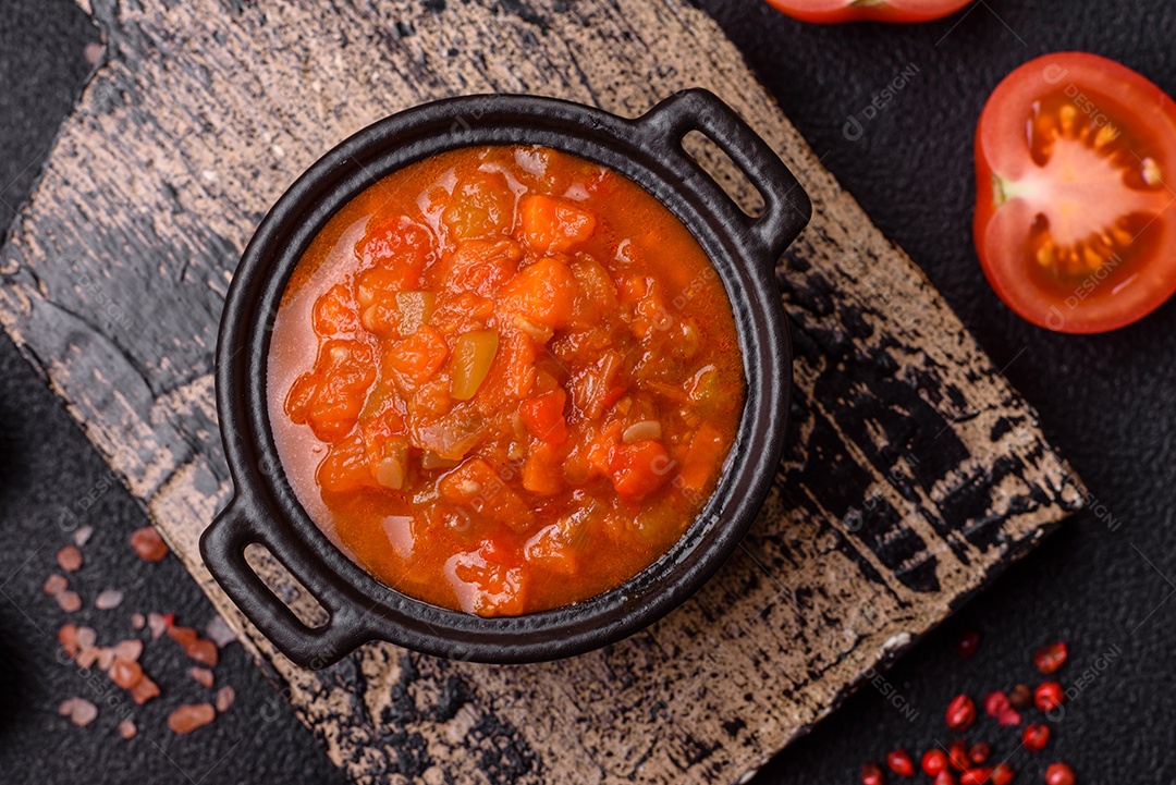 Molho encarnado ou picante com pimenta, tomate, alho, especiarias e ervas em um fundo escuro de concreto