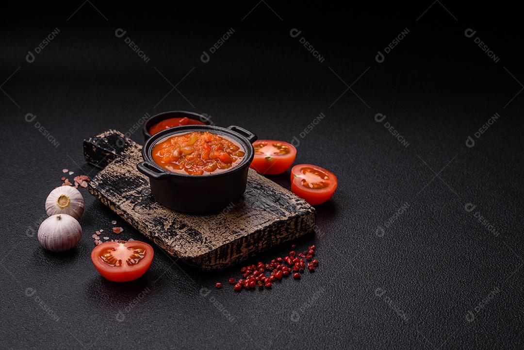 Molho encarnado ou picante com pimenta, tomate, alho, especiarias e ervas em um fundo escuro de concreto