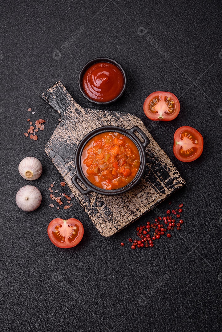 Molho encarnado ou picante com pimenta, tomate, alho, especiarias e ervas em um fundo escuro de concreto