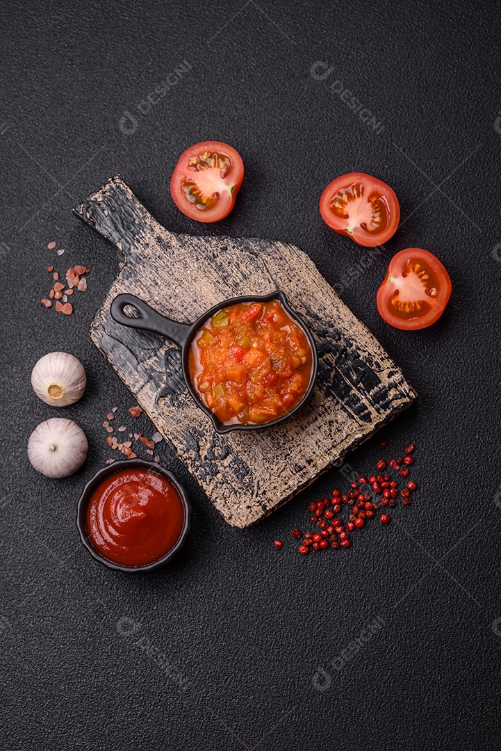 Molho encarnado ou picante com pimenta, tomate, alho, especiarias e ervas em um fundo escuro de concreto