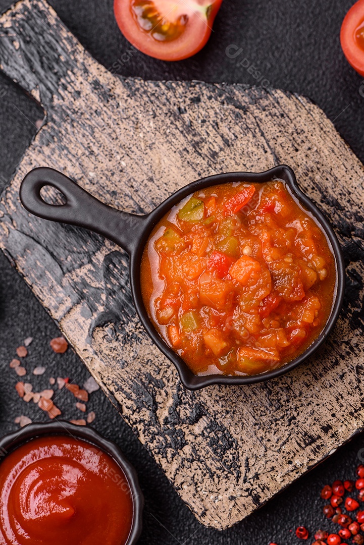 Molho encarnado ou picante com pimenta, tomate, alho, especiarias e ervas em um fundo escuro de concret