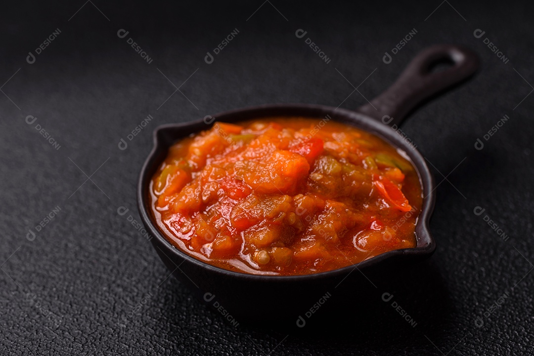 Molho encarnado ou picante com pimenta, tomate, alho, especiarias e ervas em um fundo escuro de concreto