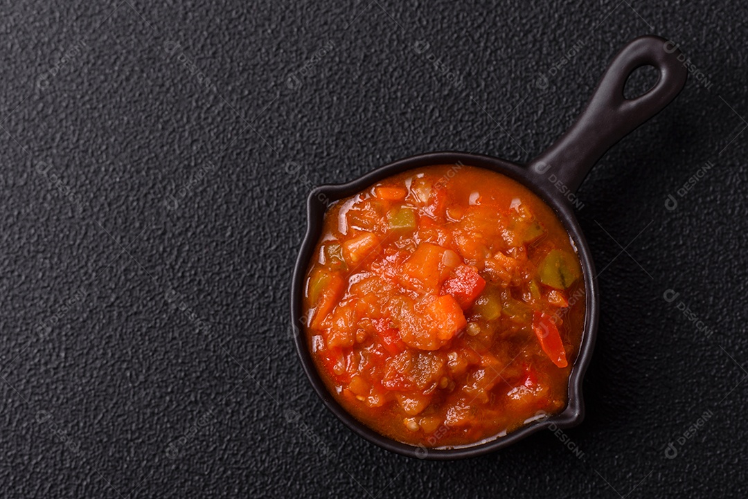 Molho encarnado ou picante com pimenta, tomate, alho, especiarias e ervas em um fundo escuro de concreto