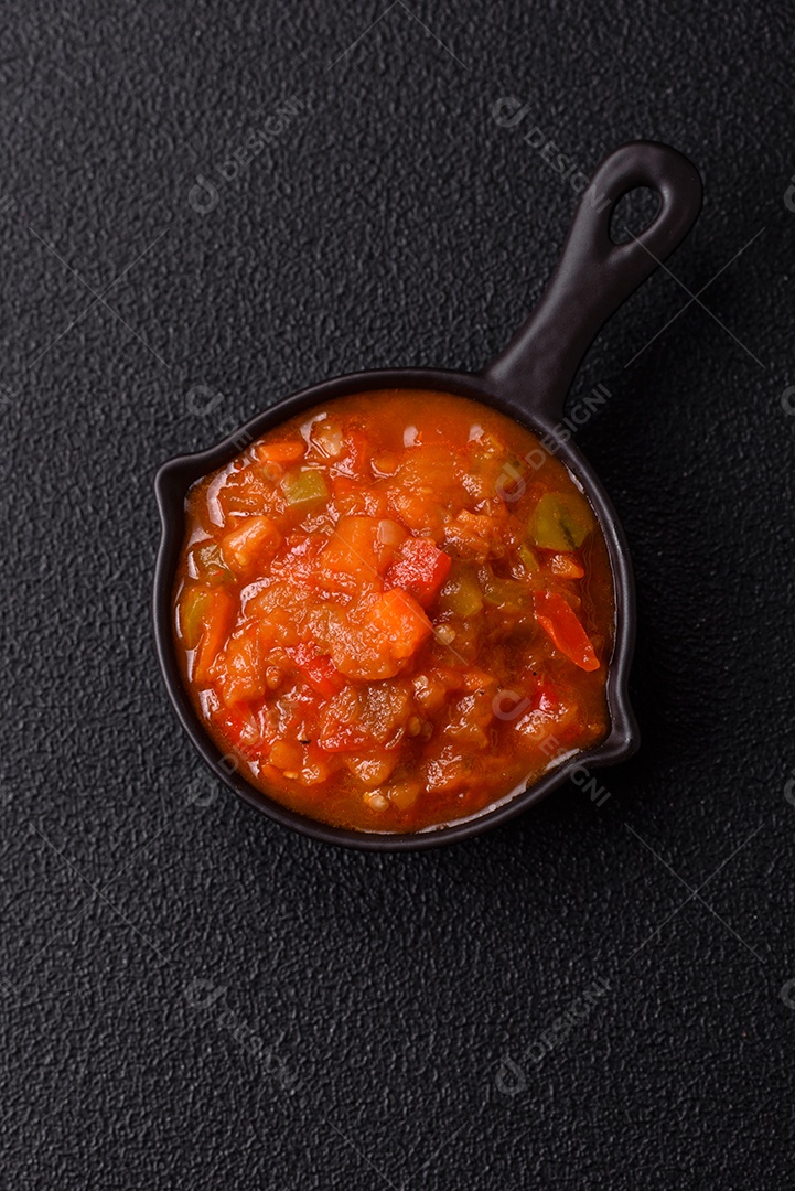 Molho encarnado ou picante com pimenta, tomate, alho, especiarias e ervas em um fundo escuro de concreto