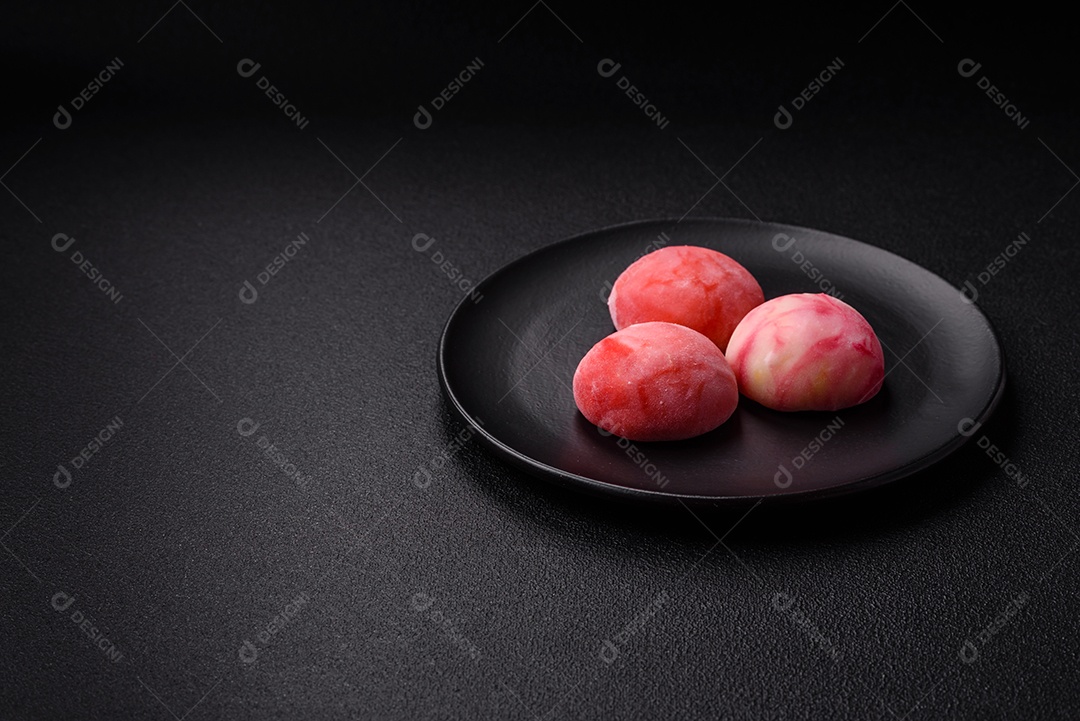 Deliciosos doces mochi asiáticos coloridos com casca de massa de arroz e recheio de frutas em fundo escuro de concreto