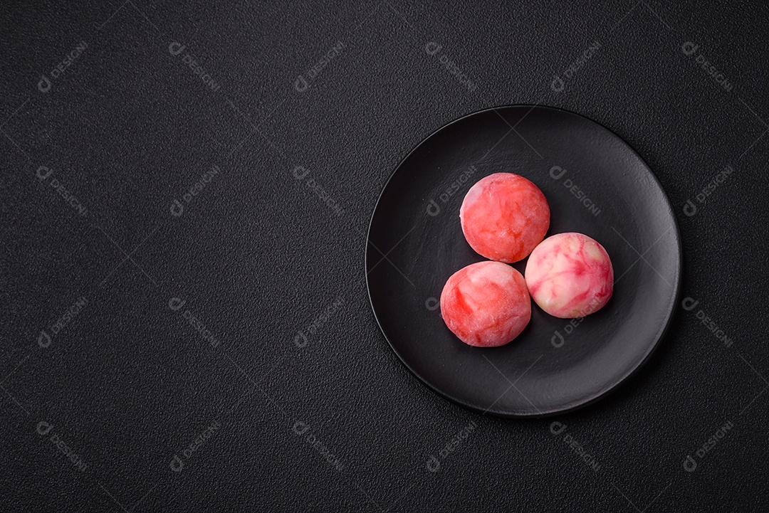 Deliciosos doces mochi asiáticos coloridos com casca de massa de arroz e recheio de frutas em fundo escuro de concret