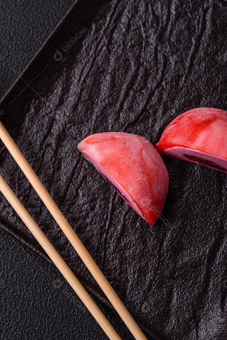 Deliciosos doces mochi asiáticos coloridos com casca de massa de arroz e recheio de frutas em fundo escuro de concreto