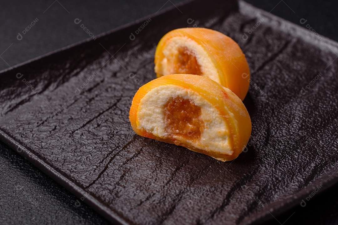 Deliciosos doces mochi asiáticos coloridos com casca de massa de arroz e recheio de frutas em fundo escuro de concreto