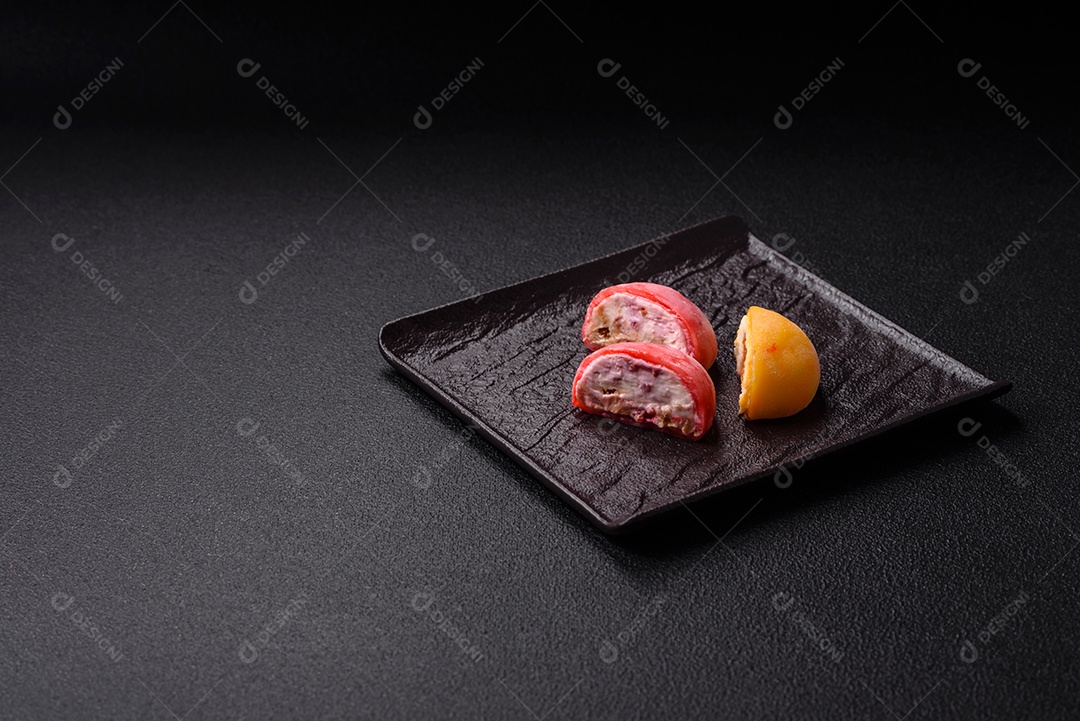 Deliciosos doces mochi asiáticos coloridos com casca de massa de arroz e recheio de frutas em fundo escuro de concreto