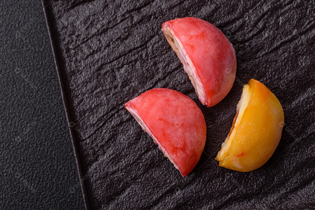 Deliciosos doces mochi asiáticos coloridos com casca de massa de arroz e recheio de frutas em fundo escuro de concreto