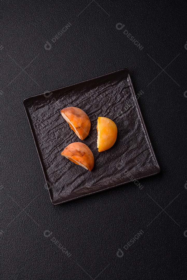 Deliciosos doces mochi asiáticos coloridos com casca de massa de arroz e recheio de frutas em fundo escuro de concreto