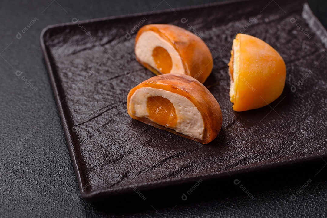 Deliciosos doces mochi asiáticos coloridos com casca de massa de arroz e recheio de frutas em fundo escuro de concreto