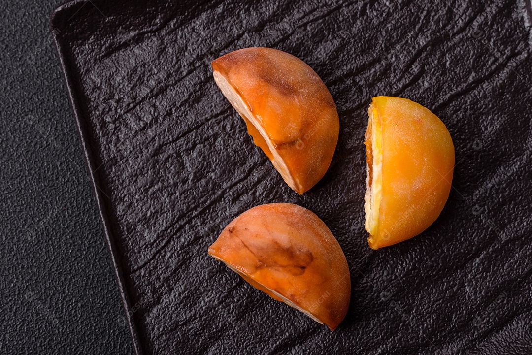 Deliciosos doces mochi asiáticos coloridos com casca de massa de arroz e recheio de frutas em fundo escuro de concreto