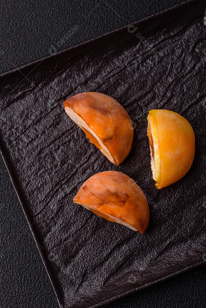 Deliciosos doces mochi asiáticos coloridos com casca de massa de arroz e recheio de frutas em fundo escuro de concreto