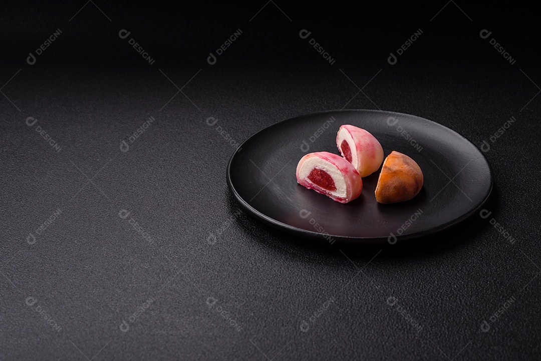 Deliciosos doces mochi asiáticos coloridos com casca de massa de arroz e recheio de frutas em fundo escuro de concreto