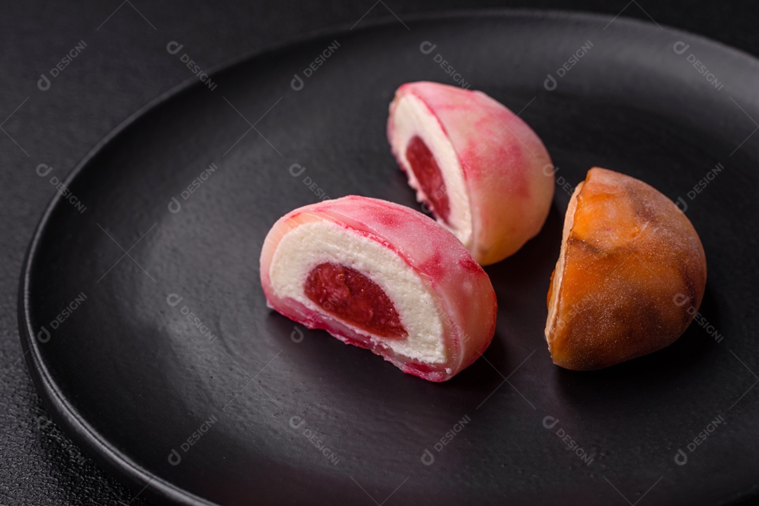 Deliciosos doces mochi asiáticos coloridos com casca de massa de arroz e recheio de frutas em fundo escuro de concreto