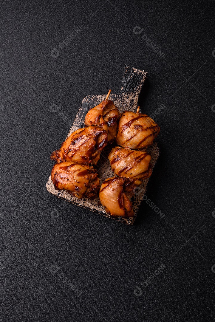 Delicioso frango assado ou espetinho de peru em um espeto com sal e especiarias em um fundo escuro de concreto