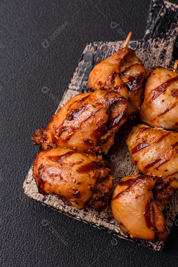 Delicioso frango assado ou espetinho de peru em um espeto com sal e especiarias em um fundo escuro de concreto