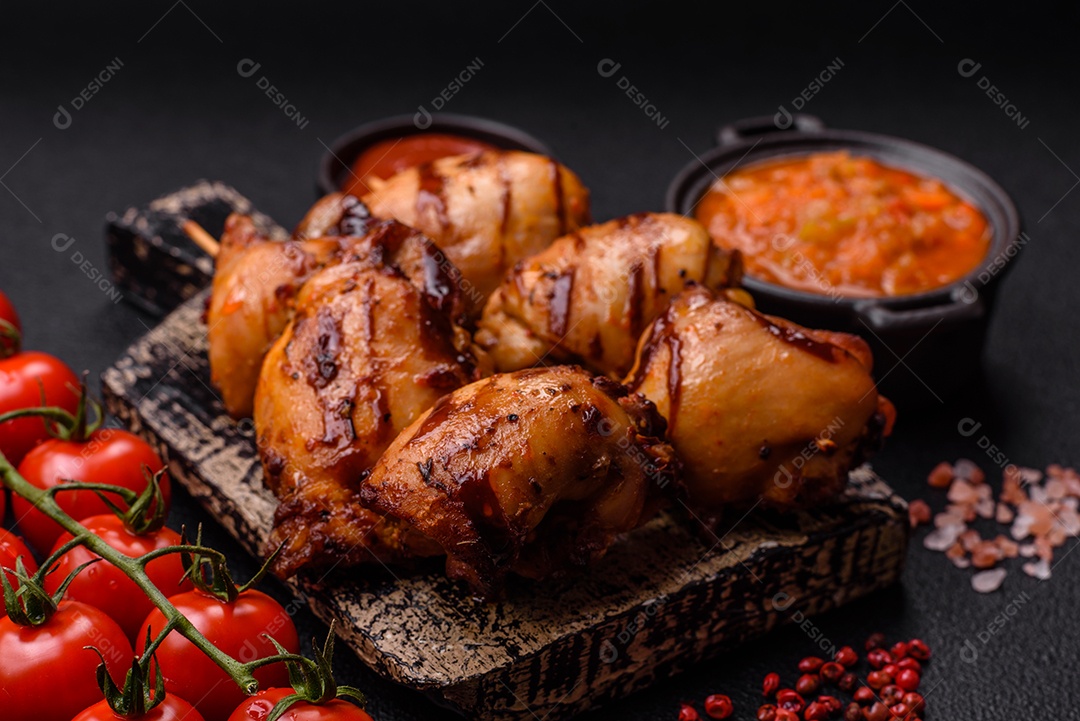 Delicioso frango assado ou espetinho de peru em um espeto com sal e especiarias em um fundo escuro de concreto
