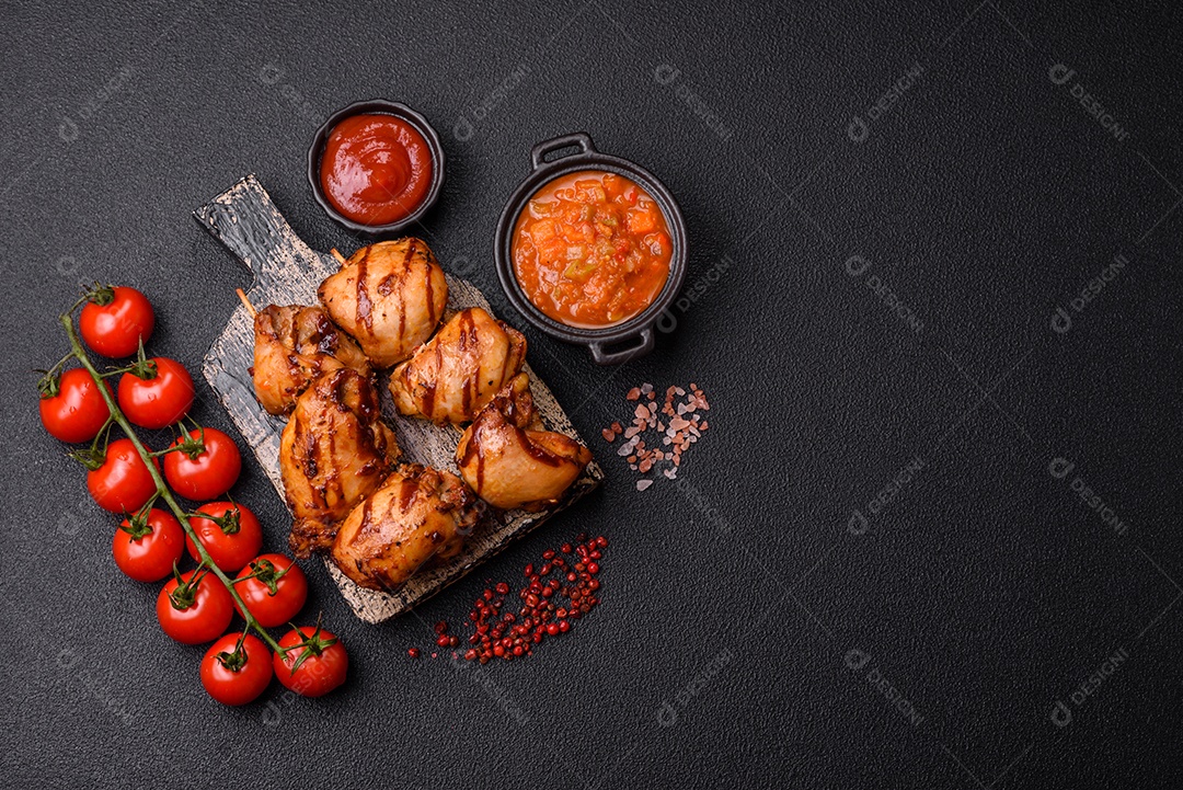 Delicioso frango assado ou espetinho de peru em um espeto com sal e especiarias em um fundo escuro de concreto