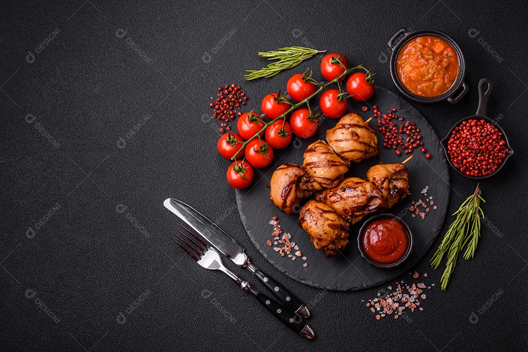 Delicioso frango assado ou espetinho de peru em um espeto com sal e especiarias em um fundo escuro de concreto