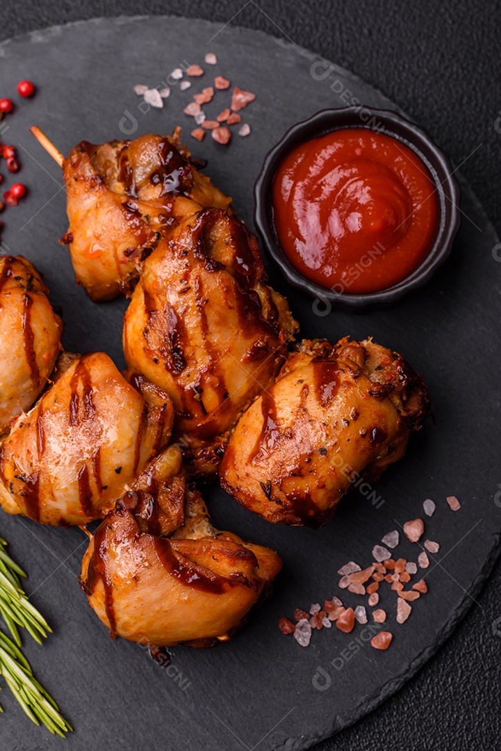 Delicioso frango assado ou espetinho de peru em um espeto com sal e especiarias em um fundo escuro de concreto