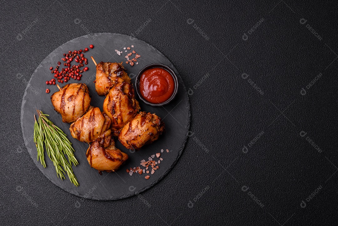 Delicioso frango assado ou espetinho de peru em um espeto com sal e especiarias em um fundo escuro de concreto