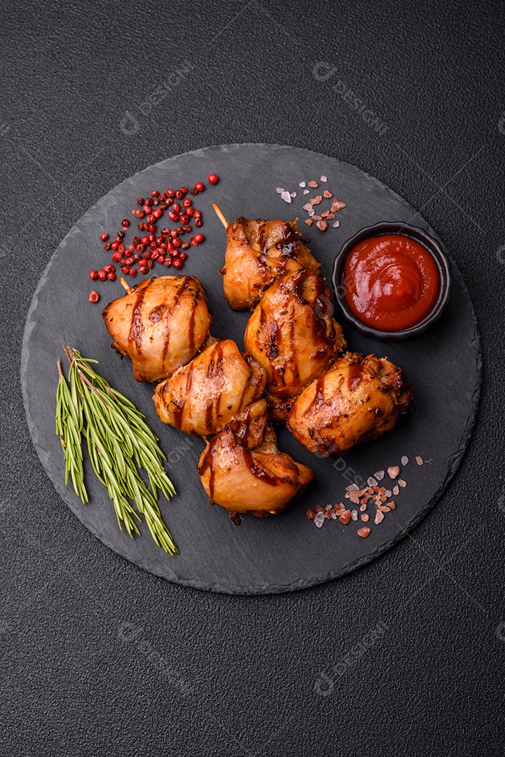 Delicioso frango assado ou espetinho de peru em um espeto com sal e especiarias em um fundo escuro de concreto